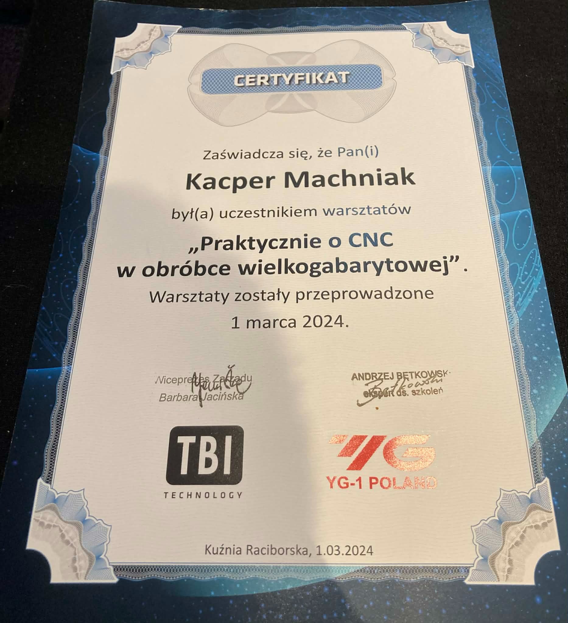 Certyfikat ukończenia warsztatów 'Praktycznie o CNC w obróbce wielkogabarytowej' dla Kacpra Machniaka, z datą 1 marca 2024, wydany przez TBI Technology i YG-1 Poland.