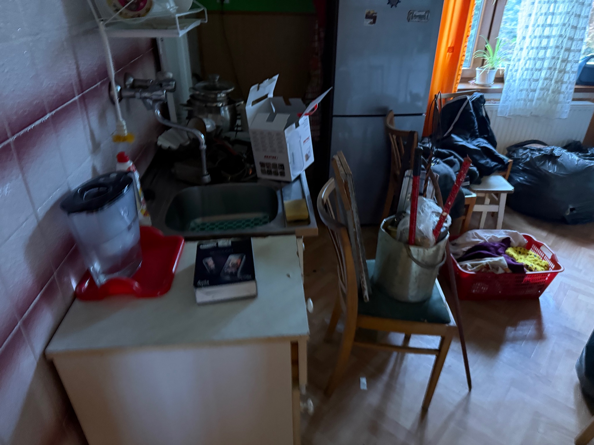 Kadr z wnętrza zagraconego mieszkania: wiadro z mopem, karton, torby, krzesła. Przygotowania do opróżniania mieszkania lub przeprowadzki. Ujęcie z perspektywy pierwszej osoby.