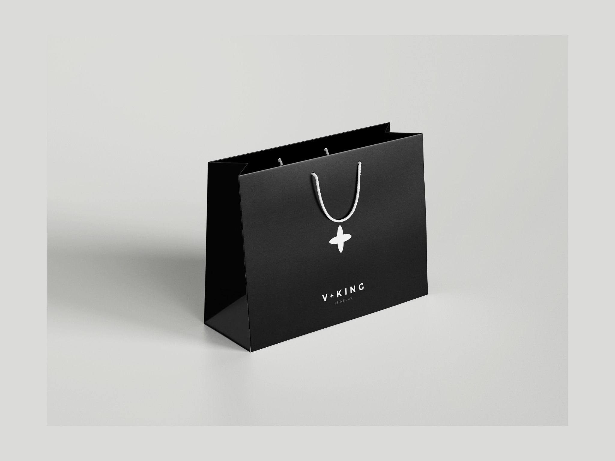 Czarna torba prezentowa z białym logo V+KING Jewelry na jasnym tle. Minimalistyczny design, elegancki wygląd, gładka powierzchnia torby.