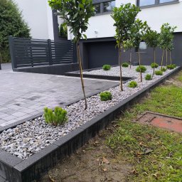 B&B Garden Usługi Ogrodnicze Hubert Rozynek - Nowoczesny ogród z rzędem drzewek i ozdobnymi krzewami, wysypany białym kamieniem, obrzeża z kostki brukowej. Minimalistyczny design ogrodu.