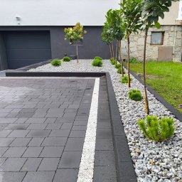 B&B Garden Usługi Ogrodnicze Hubert Rozynek - Nowoczesny ogród z równo posadzonymi drzewkami i krzewami, wysypany białym kamieniem, obok wyłożony kostką brukową. Minimalistyczny design.