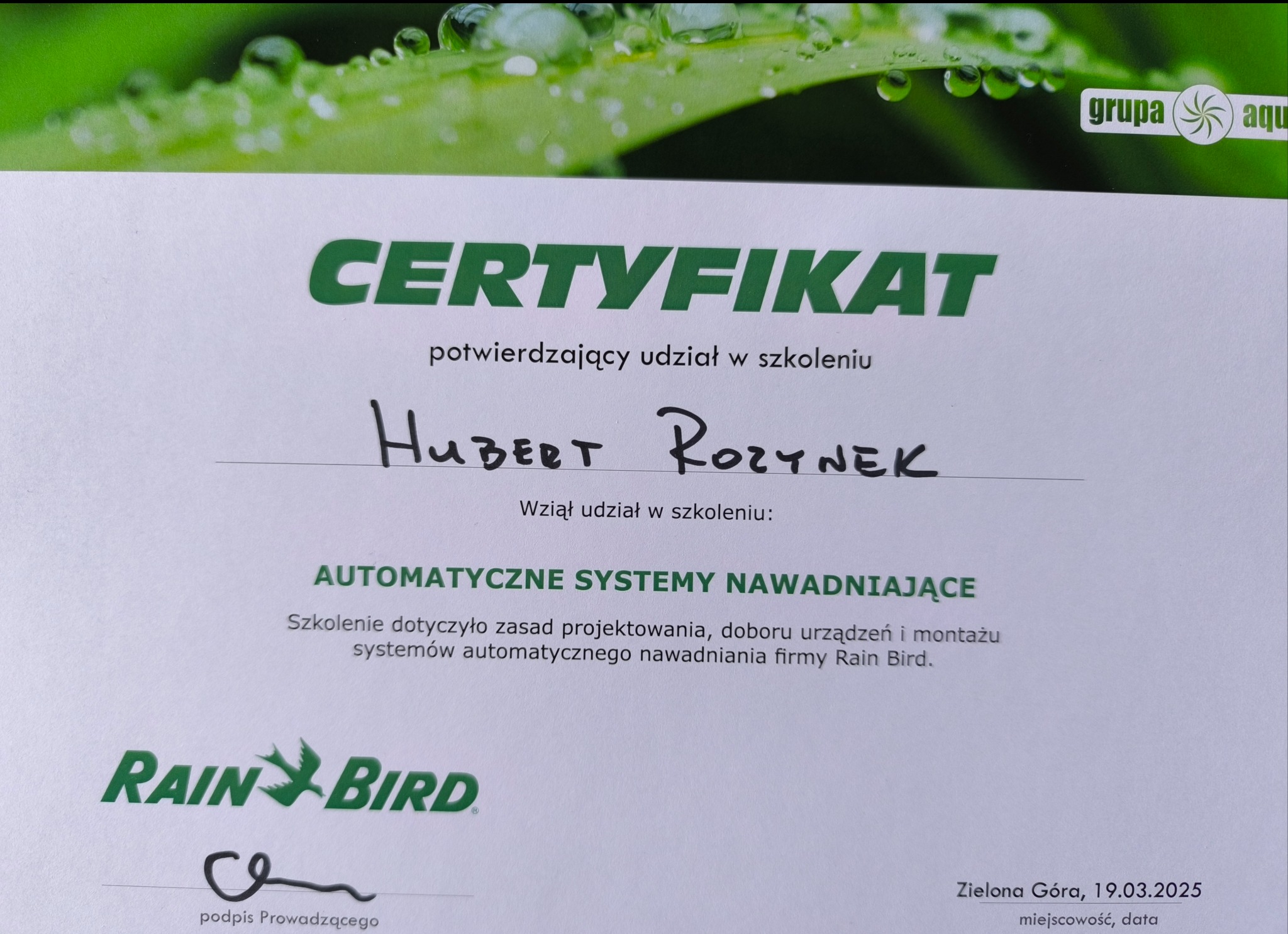 Certyfikat ukończenia szkolenia z automatycznych systemów nawadniających Rain Bird, podpisany przez Huberta Rozynek, z datą 19.03.2025.