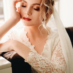 Justyna Gocel - Portret kobiety w koronkowej sukni z welonem, z delikatnym makijażem i upiętymi włosami, w miękkim świetle okiennym. Subtelny wyraz twarzy.