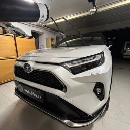 Mateusz Jankowski - Biały SUV Toyota RAV4 po myciu, zaparkowany w garażu z podniesioną bramą. Widoczne detale karoserii i reflektory. Na przednim zderzaku naklejka MobiDetail.