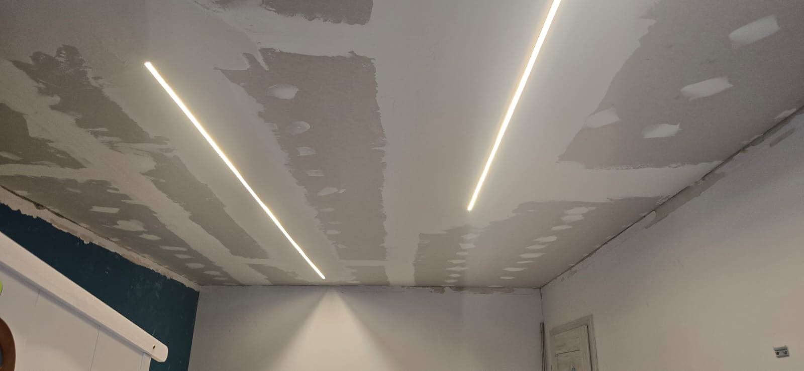 Sufit po szpachlowaniu z zamontowanym oświetleniem LED. Widoczne łączenia płyt karton-gips. Ściany częściowo pomalowane na biało i granatowo.