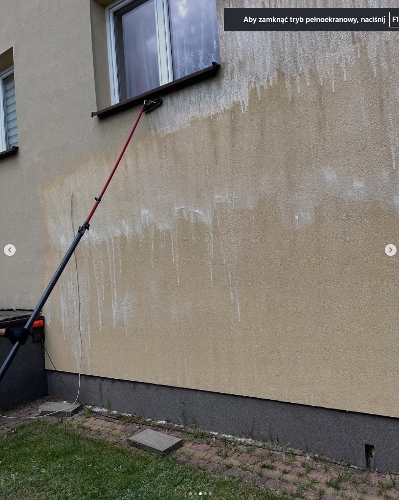 Elewacja budynku w trakcie czyszczenia z użyciem teleskopowej szczotki. Widoczne zacieki po wodzie i różnica w kolorze umytej i brudnej powierzchni.