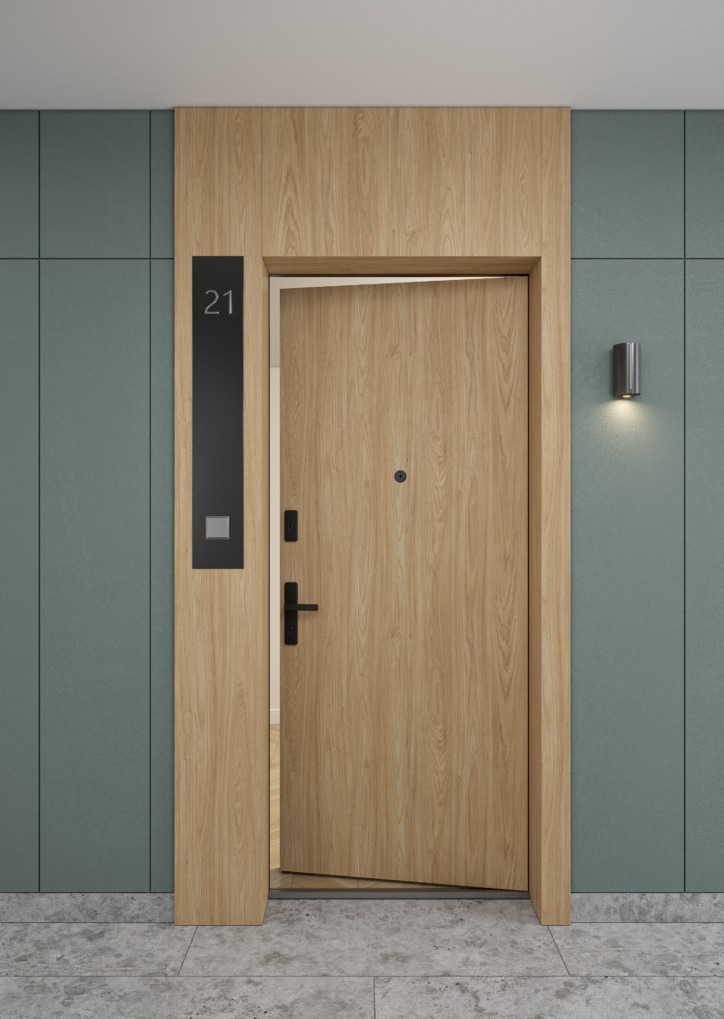 Drewniane drzwi wejściowe z numerem mieszkania '21' i czarną klamką, oświetlone kinkietem na tle zielonej ściany z panelami, częściowo otwarte.