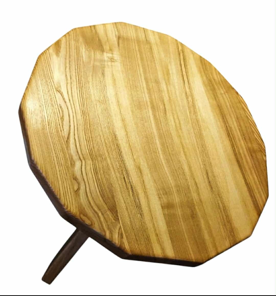 Ośmiokątny blat drewniany z widocznym usłojeniem, osadzony na pojedynczej, ciemnej nodze. Blat w odcieniach jasnego brązu, wykończony lakierem.