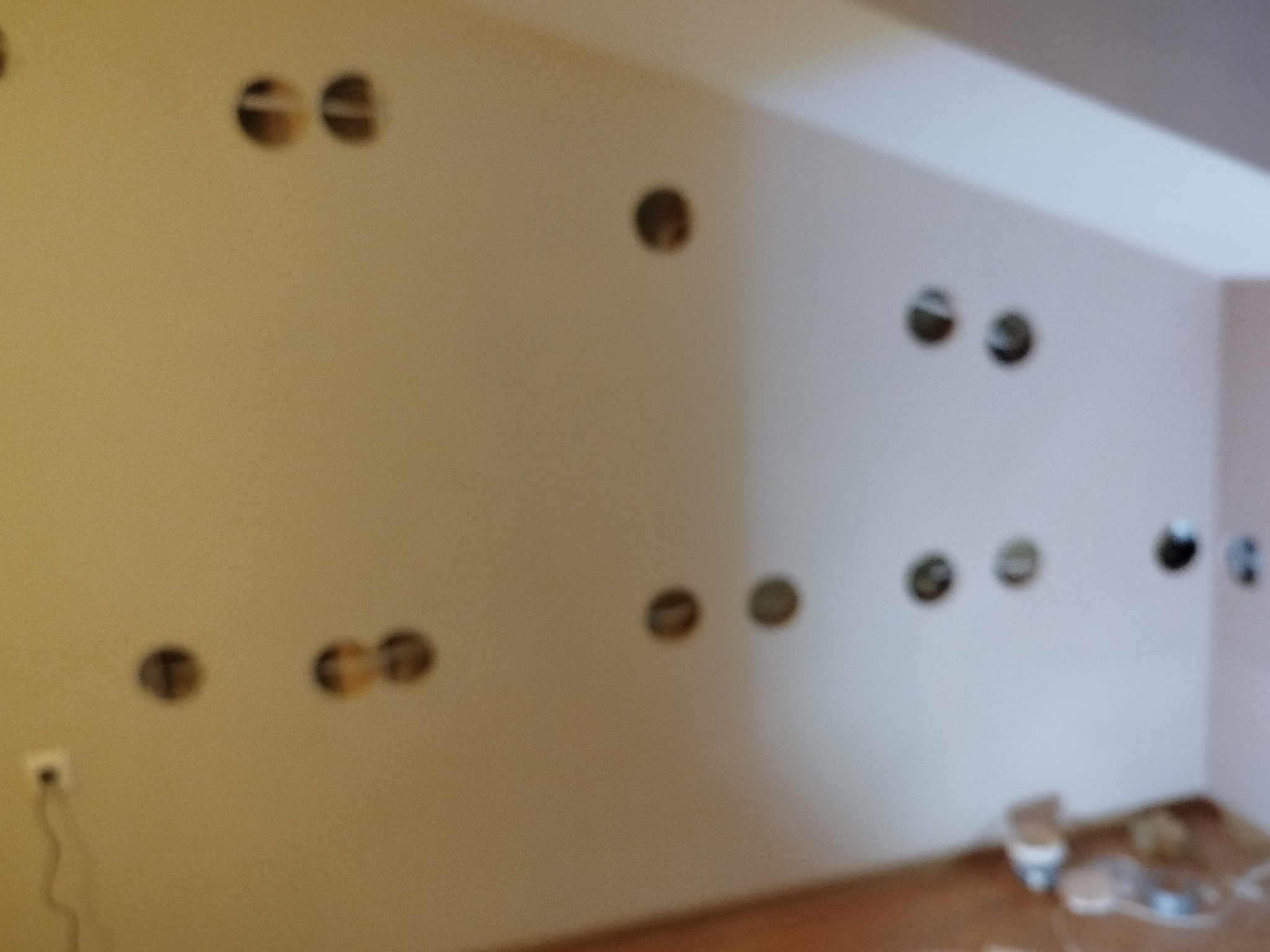 Ściana z wywierconymi otworami pod gniazdka elektryczne i włączniki, widoczne przewody. Przygotowanie do instalacji elektrycznej w nowym budynku.