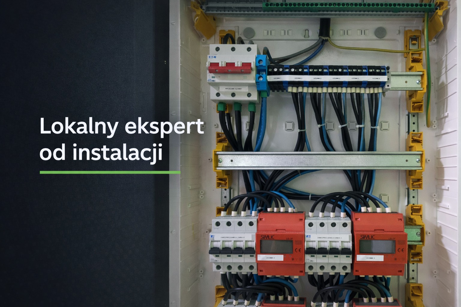 Rozdzielnia elektryczna z bezpiecznikami, przewodami i listwami zaciskowymi w białej obudowie. Widoczne elementy instalacji elektrycznej.