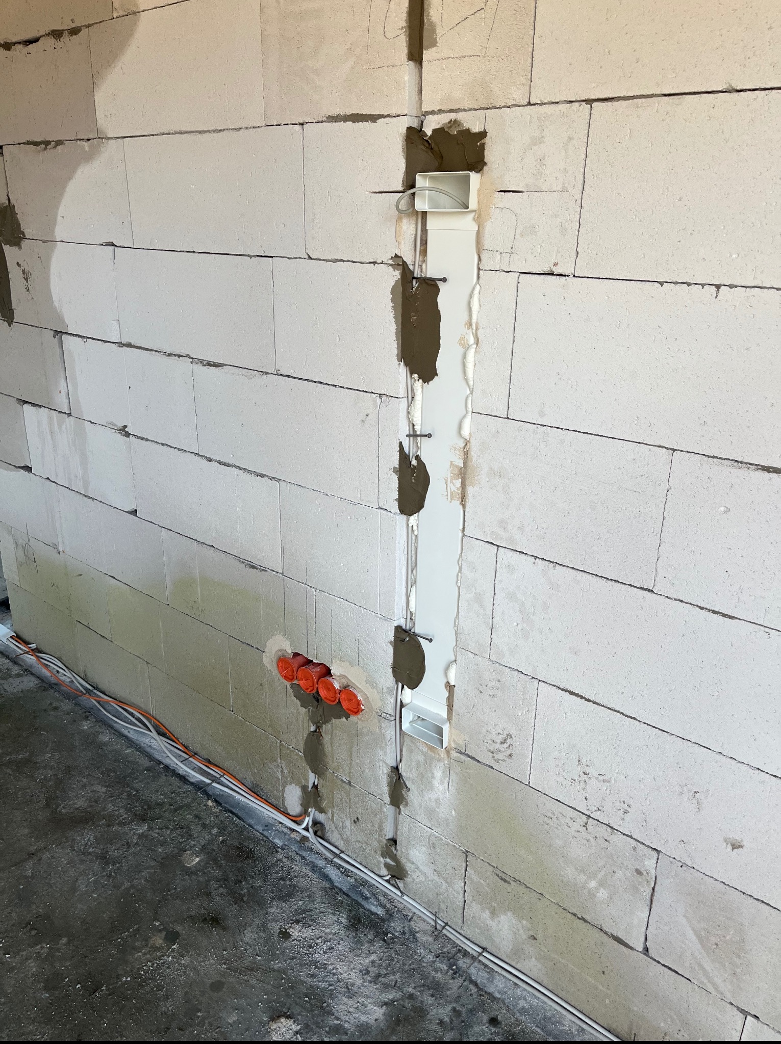 Wykute bruzdy pod instalacje elektryczne w ścianie z betonu komórkowego, widoczne kable i puszki w Pakosławiu.