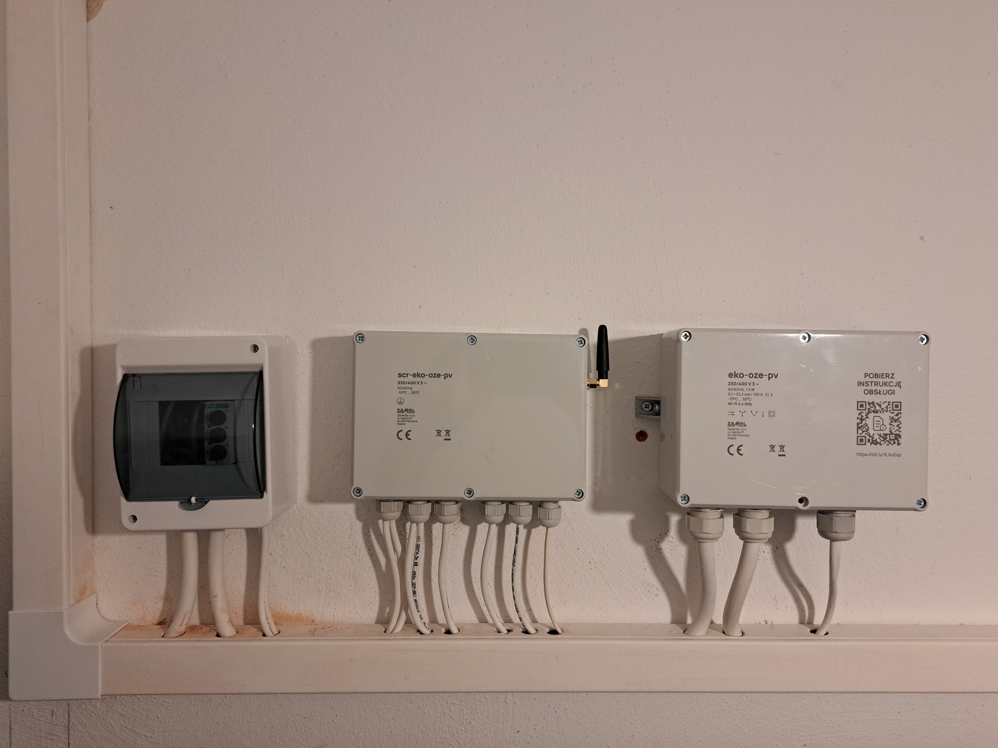 Rozdzielnica elektryczna i dwa moduły sterujące z przewodami na ścianie. Elementy instalacji elektrycznej wewnątrz budynku.