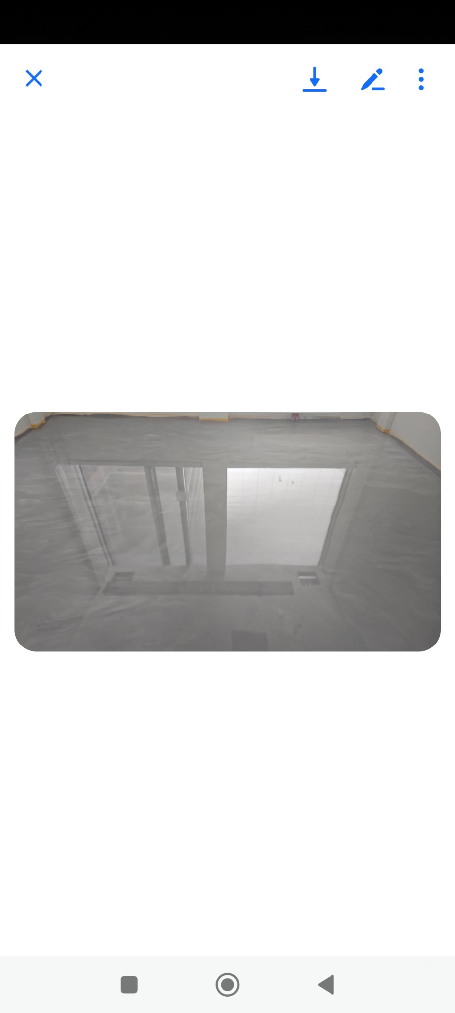 Błyszcząca, szara posadzka w pomieszczeniu z oknem, zabezpieczona żółtą taśmą przy ścianach. Widoczne odbicie okna w gładkiej powierzchni podłogi.