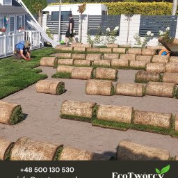 Robert Pilecki Consulting - Układanie trawy z rolki na przygotowanym terenie. Widoczny pracownik, rolki trawy i fragment ogrodu z domkiem dla dzieci i ogrodzeniem panelowym.