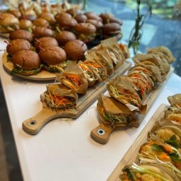 Restaurant 1 Sp. z o.o. - Elegancki catering: mini burgery na drewnianej desce i azjatyckie bułeczki bao z warzywami, podane na deskach z uchwytami, idealne na imprezę firmową.
