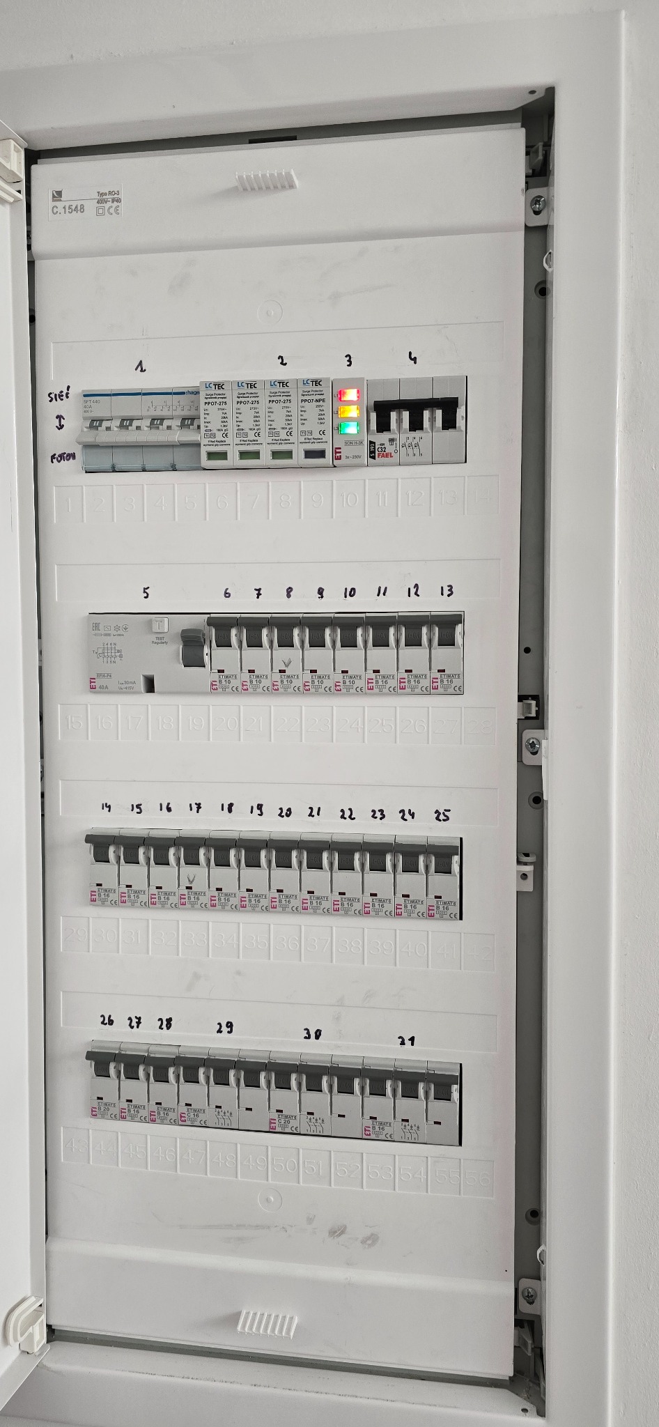 Rozdzielnica elektryczna w domu jednorodzinnym z modułami i oznaczeniami, widok z bliska, instalacja tradycyjna, osprzęt ETI i LC-TEC, biała obudowa.