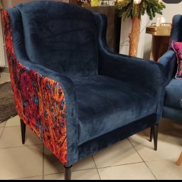 X-Mara Dzianis Khmara - Granatowy fotel z weluru z wzorzystym, kolorowym tyłem. Elegancki mebel z wysokim oparciem i ciemnymi nóżkami, widoczny fragment drugiego fotela w tle.