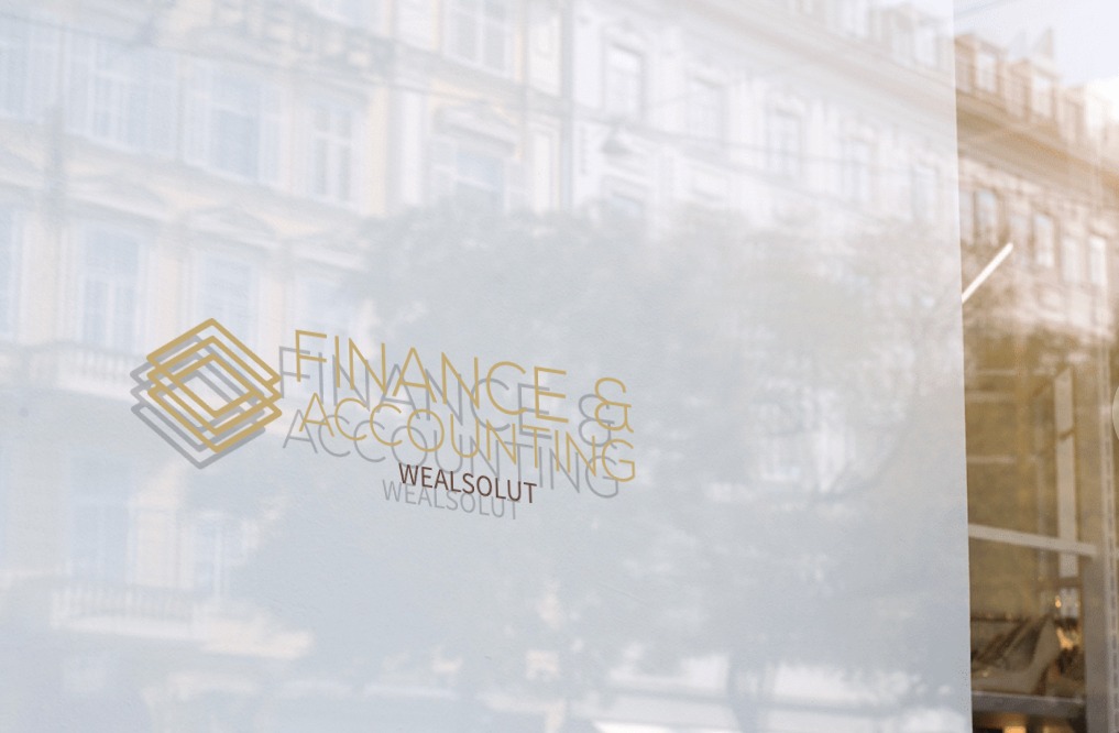 Logo 'Finance & Accounting Wealsolut' na szklanej powierzchni z odbiciem budynku w tle. Złote i szare litery, nowoczesny design.