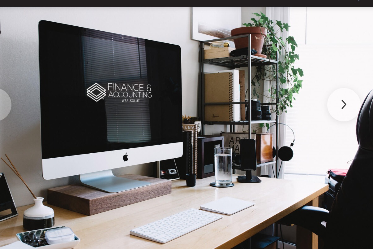 Biuro z komputerem wyświetlającym logo Finance & Accounting. Minimalistyczny design, drewniane biurko, roślina doniczkowa i akcesoria biurowe tworzą profesjonalną atmosferę.