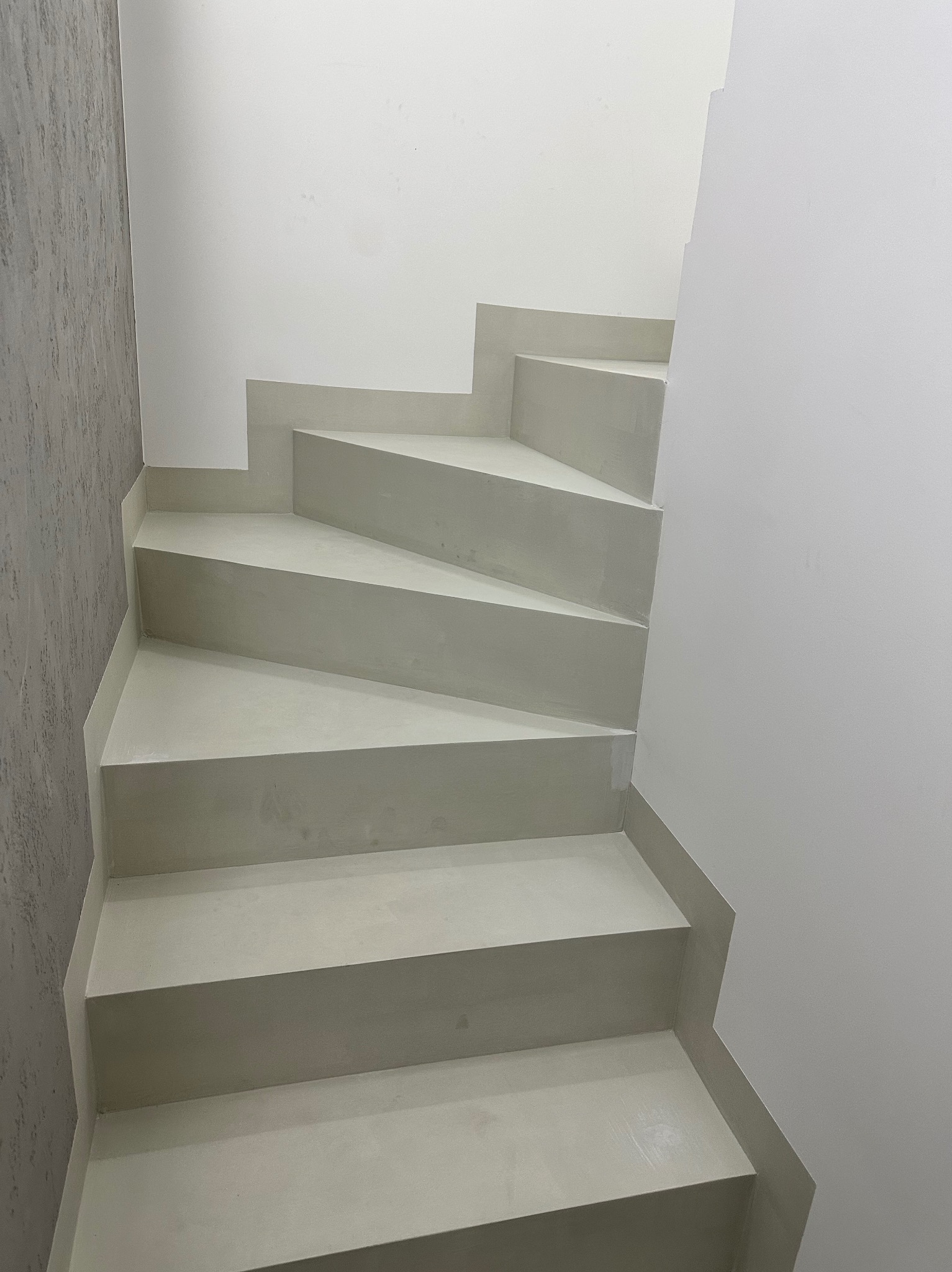 Schody wykończone mikrocementem w odcieniach szarości, minimalistyczny design, gładka powierzchnia. Realizacja w Warszawie.