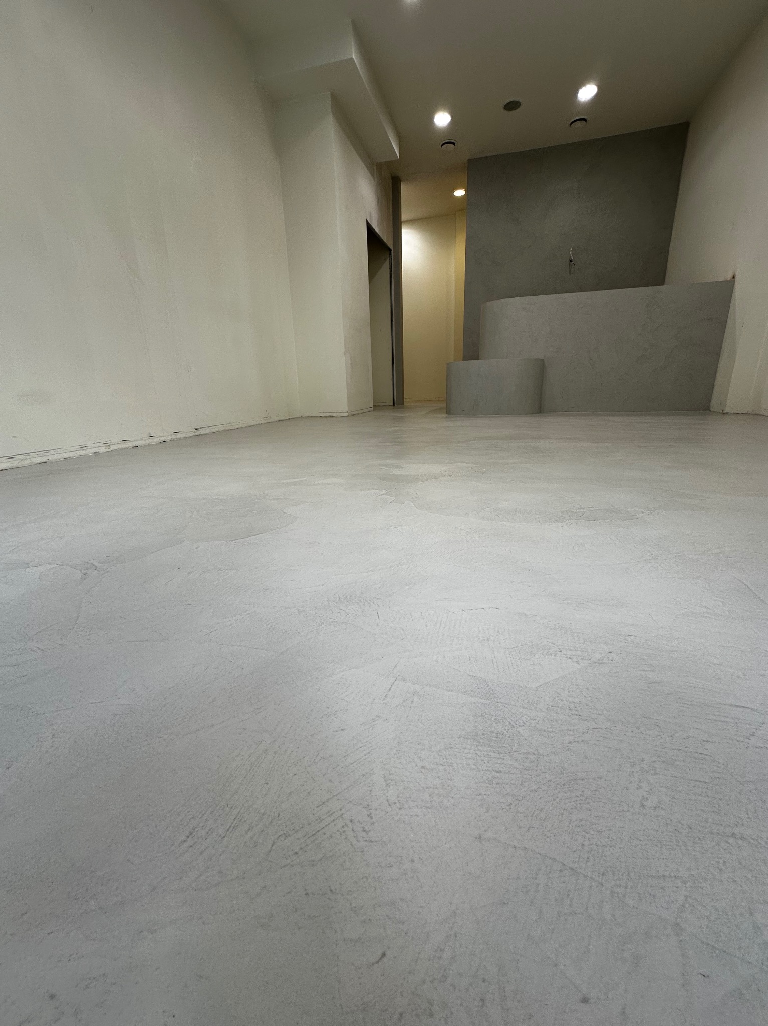 Jasnoszara posadzka z efektem dekoracyjnym w pustym pomieszczeniu biurowym. Ściany w odcieniach bieli i szarości, minimalistyczny design.