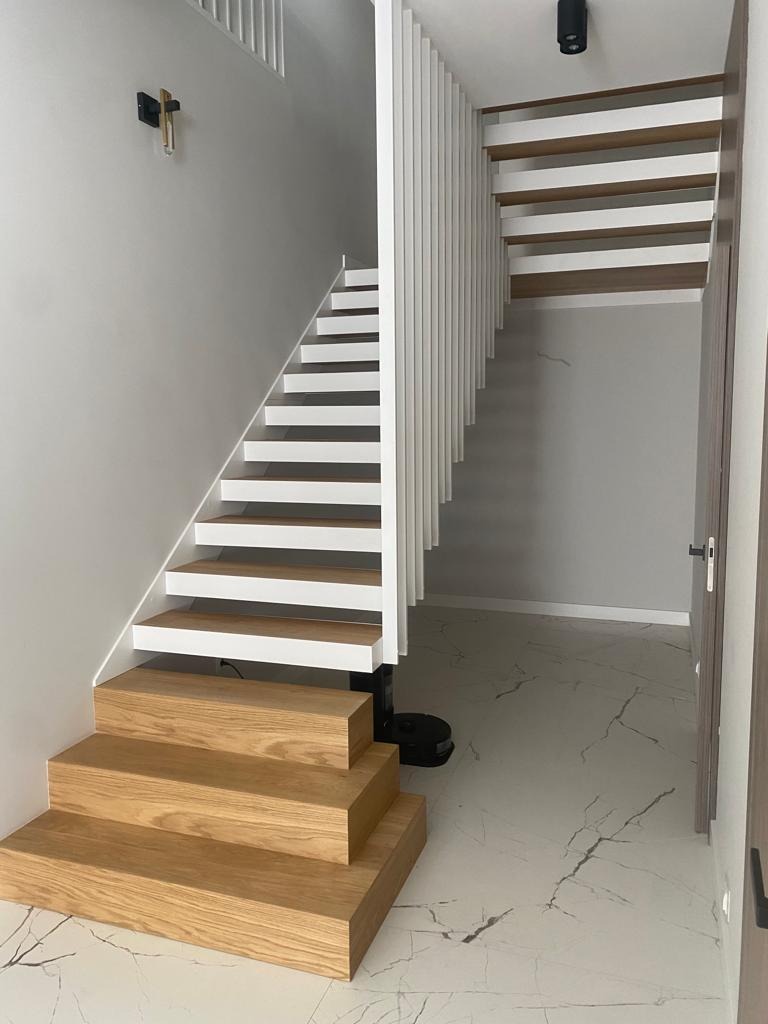 Nowoczesne schody z drewnianymi stopniami i białymi elementami konstrukcyjnymi, minimalistyczny design, widok z dołu, marmurowa podłoga.