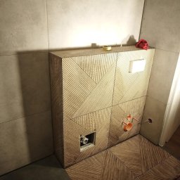 Maiki - Wykończona łazienka z zabudową WC w drewnopodobne, geometryczne wzory. Widoczne przyłącza i otwór rewizyjny. Na górze leżą narzędzia i czerwona szmatka.