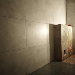 Maiki - Wykończona łazienka z beżowymi płytkami na ścianach i podłodze. Zabudowa WC z drewnopodobnymi panelami z ukośnymi wzorami. Widoczne przyłącza wodne.