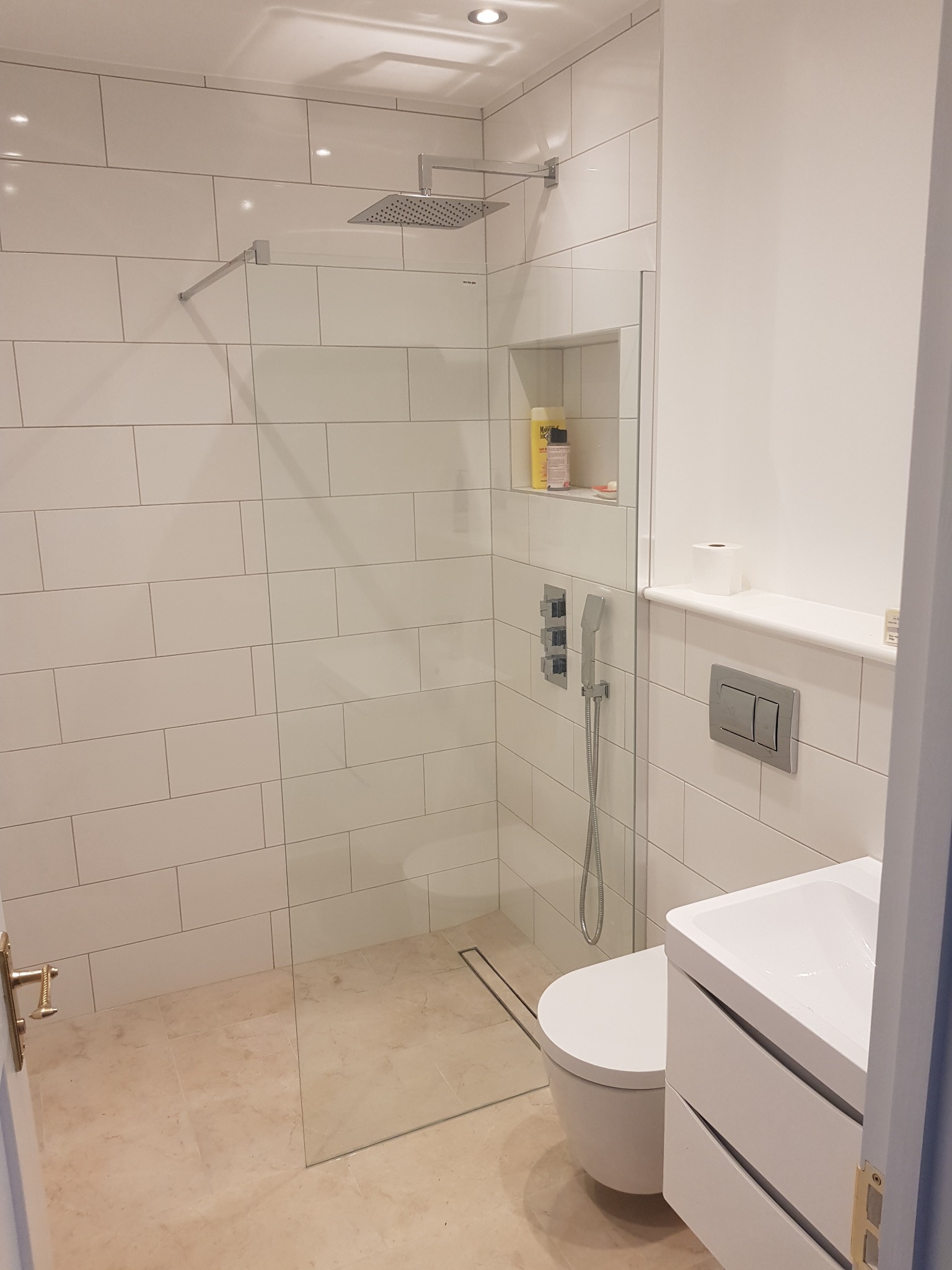 Wykończona łazienka z kabiną typu walk-in, białą armaturą i beżowymi płytkami podłogowymi w Hecznarowicach. Minimalistyczny design z wnęką na kosmetyki.