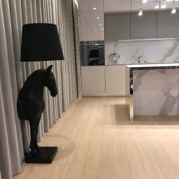 IPERFE - Nowoczesna kuchnia z marmurowym blatem i oświetleniem punktowym, uzupełniona o lampę podłogową w kształcie konia, stojącą obok zasłon.