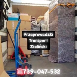 Przeprowadzki Transport Zieliński - Wnętrze busa załadowanego kartonami i meblami zabezpieczonymi folią stretch, w tle wózek transportowy. Gotowość do transportu.