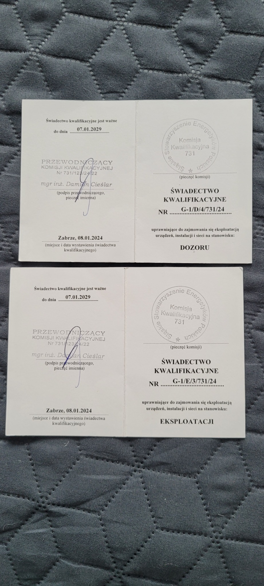 Dwa świadectwa kwalifikacyjne z pieczęciami i podpisami, uprawniające do eksploatacji urządzeń, instalacji i sieci, leżące na szarym, pikowanym tle.