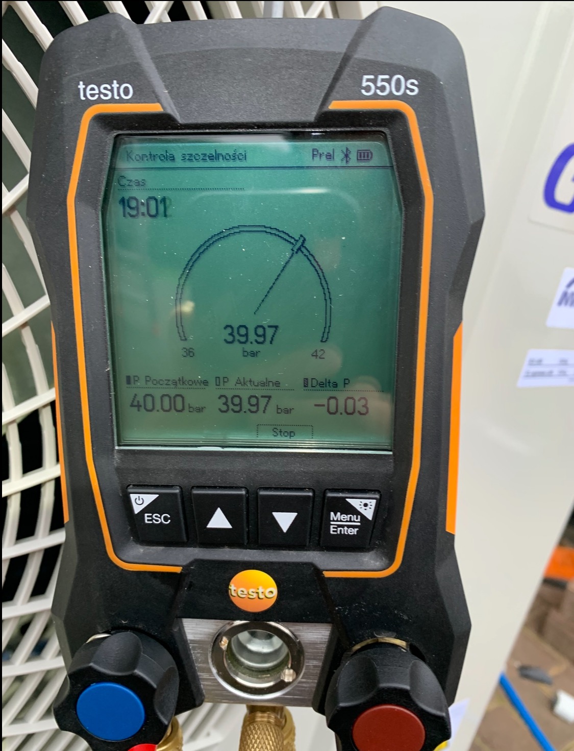 Manometr cyfrowy Testo 550s z widocznym wskazaniem ciśnienia 39.97 bar podczas kontroli szczelności instalacji. Widoczne przyłącza i elementy sterujące urządzenia.