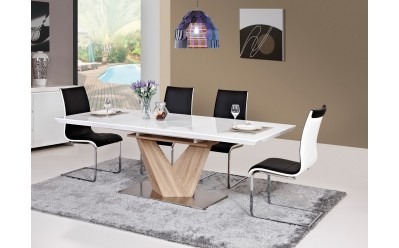 Nowoczesny stół z białym blatem i drewnianą podstawą w kształcie litery V, otoczony krzesłami na srebrnym dywanie, w jasnym wnętrzu z widokiem na basen.