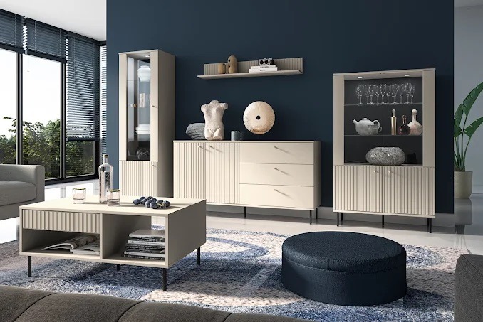 Nowoczesny salon z beżowymi meblami w stylu skandynawskim, z akcentami granatowymi, oświetlony naturalnym światłem wpadającym przez duże okno.