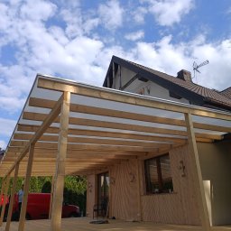 POLIMONTAŻ SZYMON ARCZEWSKI - Nowoczesna altana z drewnianą konstrukcją i przezroczystym zadaszeniem, widoczna na tle błękitnego nieba z chmurami. Czerwony samochód dostawczy w tle sugeruje etap budowy.