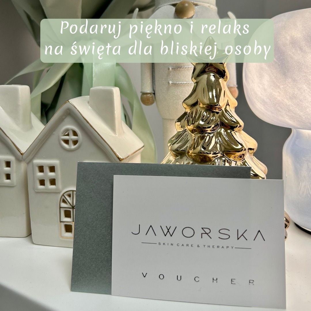 Świąteczny voucher Jaworska Skin Care & Therapy na tle dekoracji: ceramiczne domki, złota choinka i dziadek do orzechów. Idealny prezent na święta.