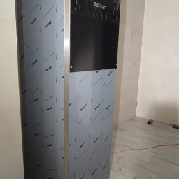 AD-SERWIS ALEKSANDRA BIELIŃSKA - Nowoczesny piec gazowy IZZI FAST z podłączeniem rur w pomieszczeniu w trakcie wykończenia, widoczne płyty gipsowe na suficie.