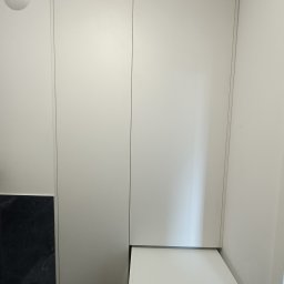 ADRIAN Czen - Biała szafa wnękowa z pralką Bosch w łazience. Minimalistyczny design, gładkie fronty, oświetlenie sufitowe. Funkcjonalne rozwiązanie do małych przestrzeni.