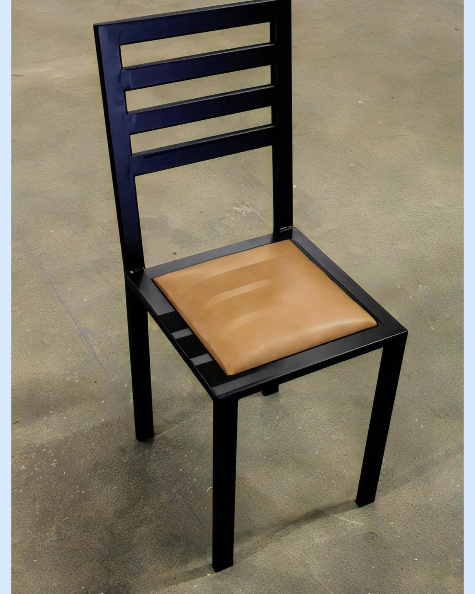 Metalowe krzesło z brązowym siedziskiem na szarym tle. Minimalistyczny design, czarne ramy, proste linie. Widok z góry, oświetlenie studyjne.