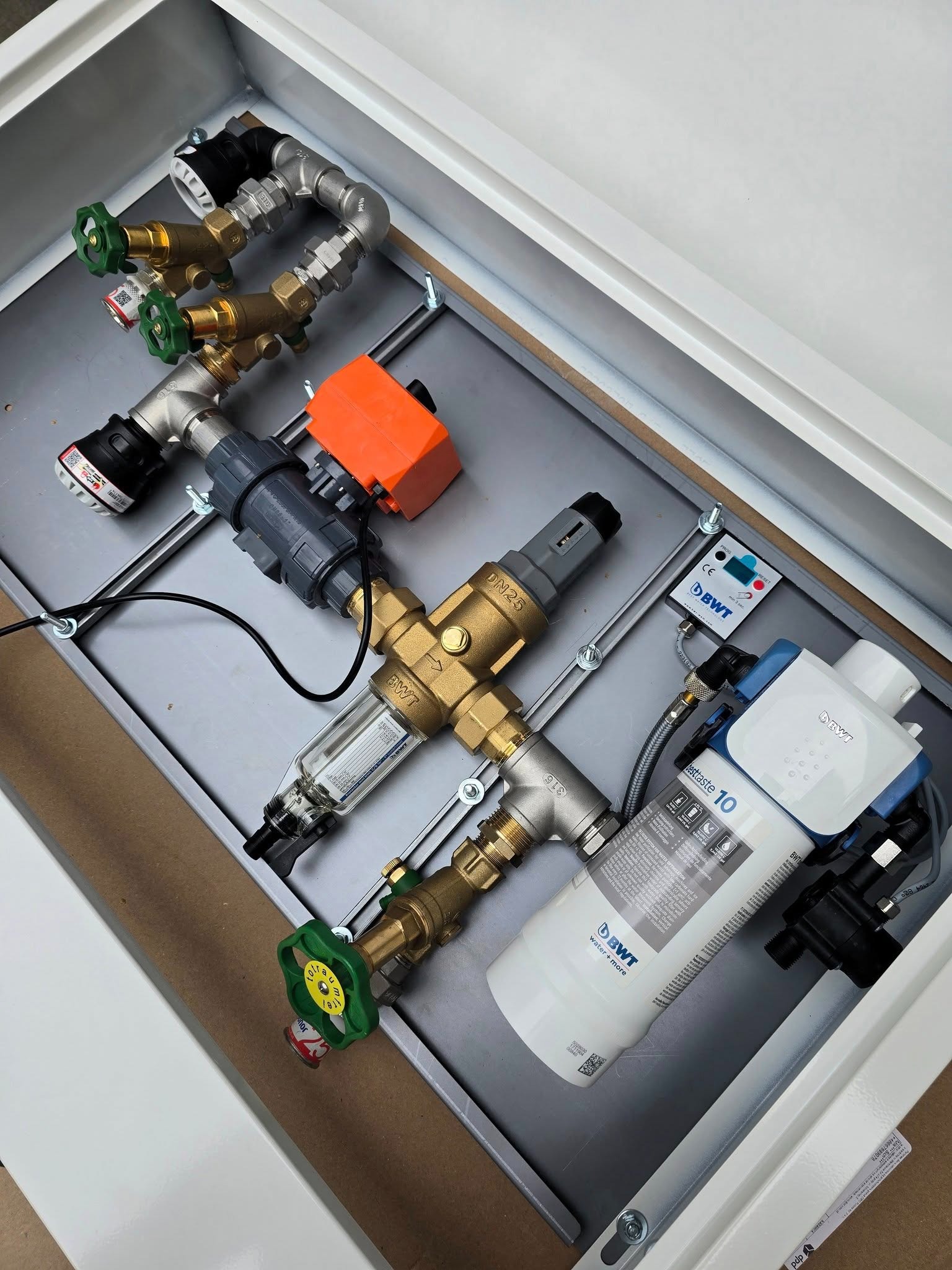 Węzeł wodny w metalowej skrzynce: zawory, filtry BWT, reduktor ciśnienia i sterownik. Kompletna instalacja wodna w estetycznej obudowie.