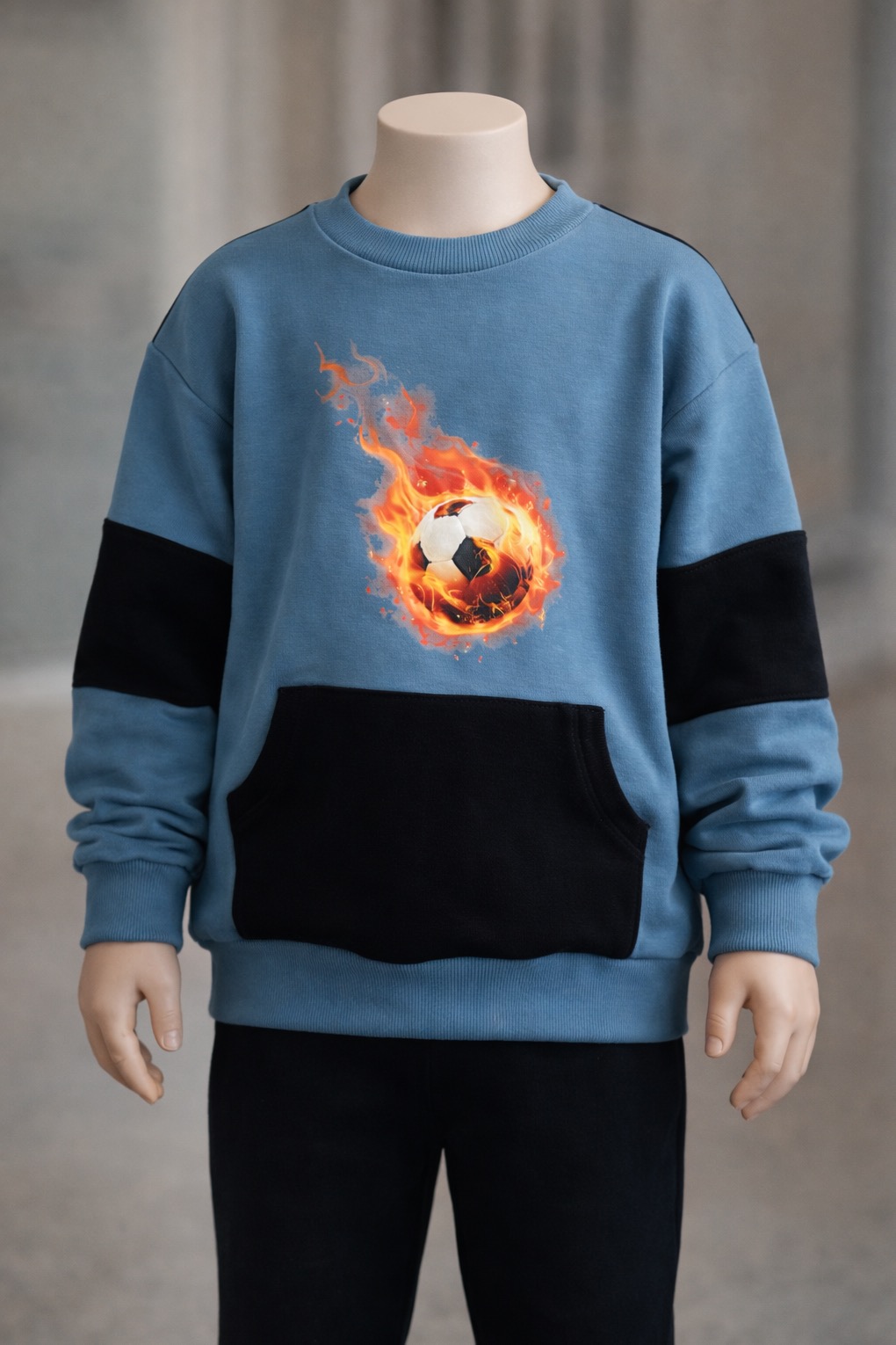 Błękitna bluza dziecięca z czarnymi wstawkami i nadrukiem płonącej piłki na manekinie, prezentacja odzieży dziecięcej.