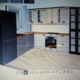 Warmińskie Domy PATRYK GICZEWSKI - Wizualizacja kuchni z zabudową w odcieniach szarości, bieli i czerni. Górne szafki z przeszkleniami, dolne pełne. Widoczny sprzęt AGD. Ujęcie z perspektywy.