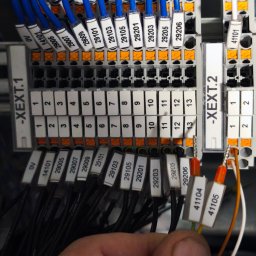 AutomatykaElektrykaDruk3D Zbigniew Obręczarek - Szczegółowe ujęcie panelu elektrycznego z oznaczonymi przewodami, widoczne złącza i etykiety z numerami, instalacja w trakcie podłączania przez elektryka.