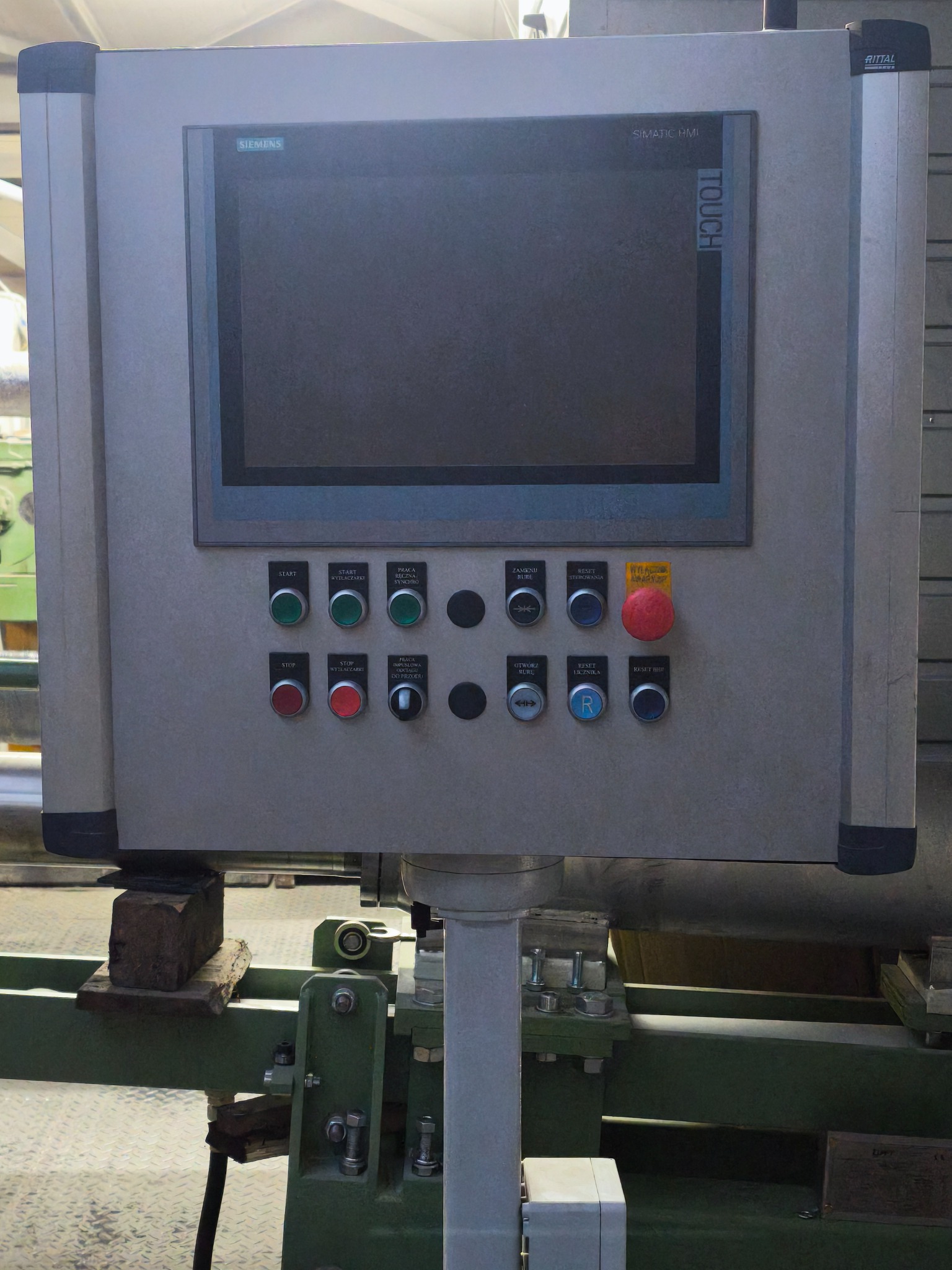 Panel sterowania maszyny z ekranem dotykowym Siemens Simatic HMI i przyciskami start/stop, reset. Widoczne elementy konstrukcyjne maszyny w tle.
