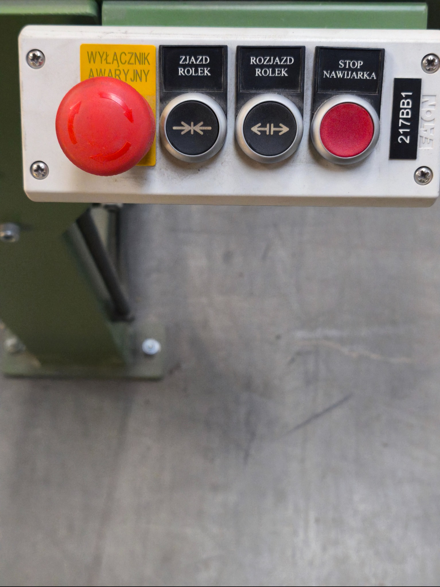 Panel sterowania maszyny z przyciskiem awaryjnym, przyciskami kierunkowymi i przyciskiem stop. Widoczne oznaczenia w języku polskim i numer seryjny.