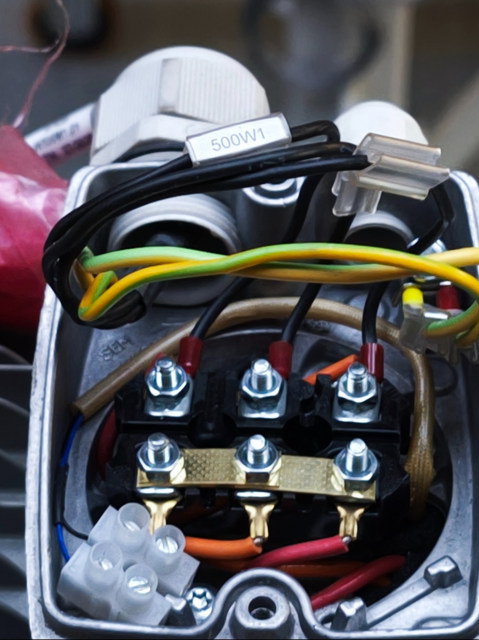 Szczegółowe zbliżenie na podłączenia elektryczne wewnątrz metalowej obudowy silnika, widoczne kable w różnych kolorach i złączki, etykieta z oznaczeniem 500W1.
