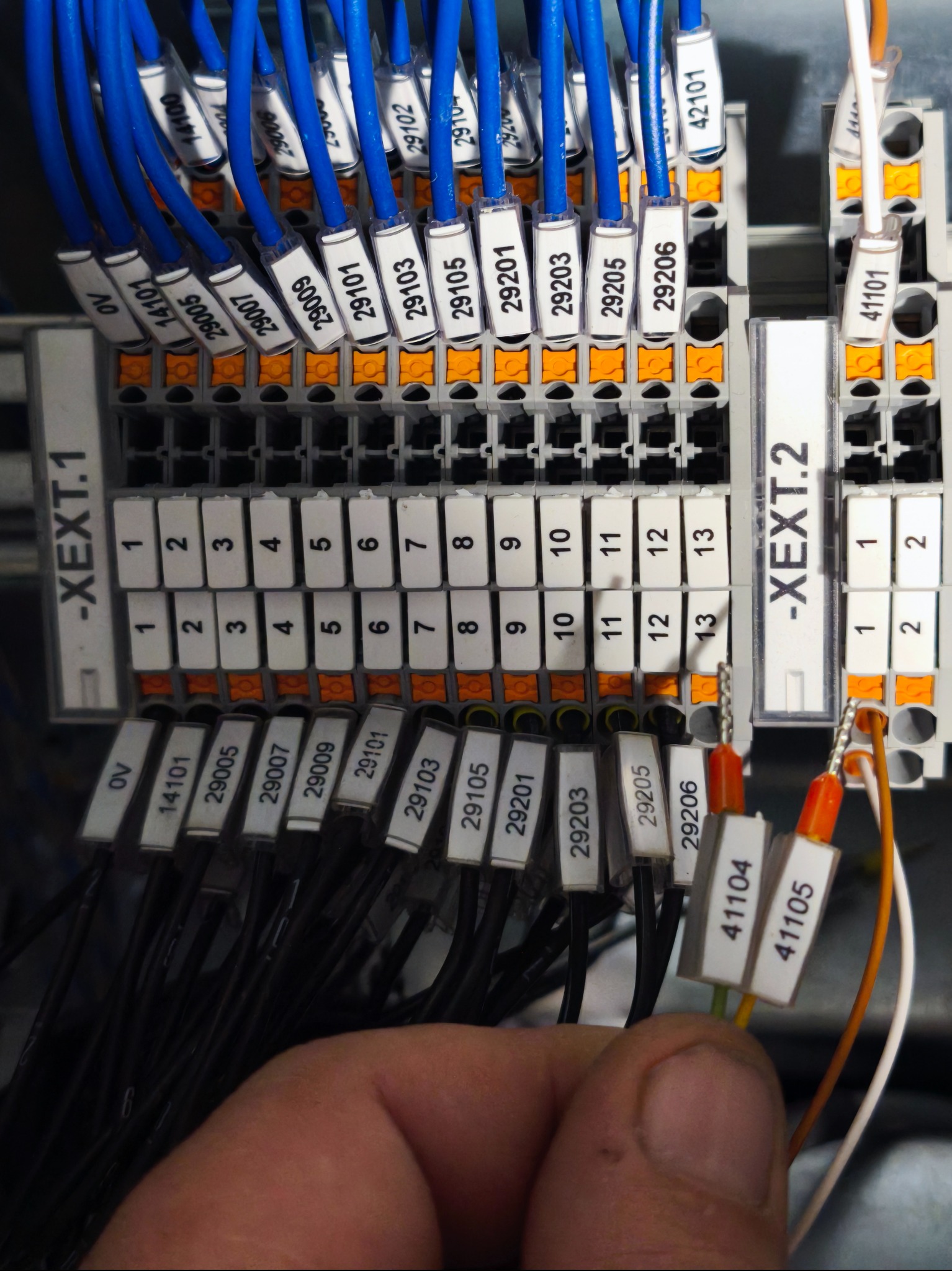 Szczegółowe ujęcie panelu elektrycznego z oznaczonymi przewodami, widoczne złącza i etykiety z numerami, instalacja w trakcie podłączania przez elektryka.