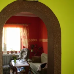 Arched doorway with textured finish, leading to a living room with red walls and patterned curtains, viewed from a room with lime green walls.