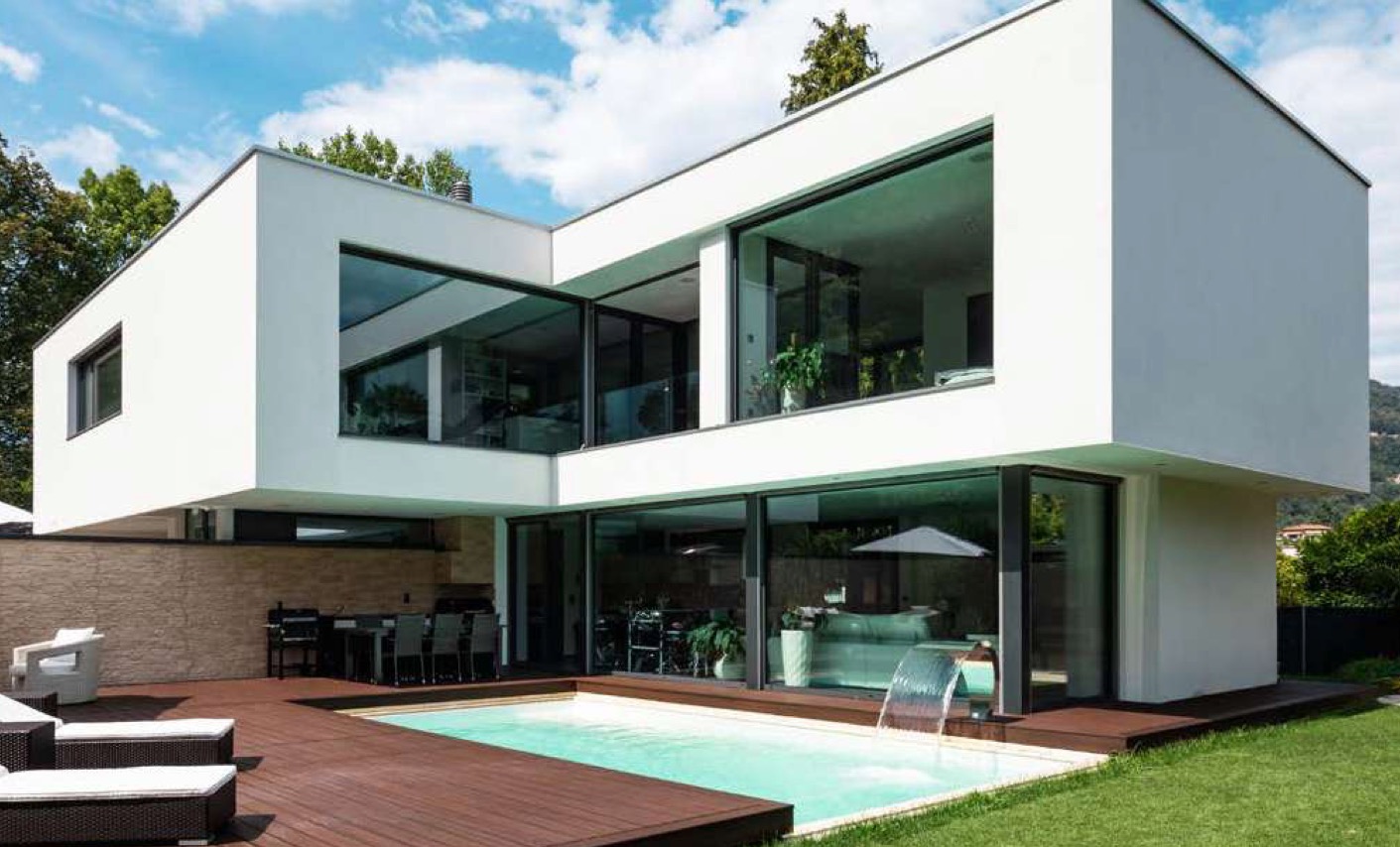 Nowoczesny dom z dużymi oknami aluminiowymi i basenem, minimalistyczna architektura, jasne wnętrza widoczne przez przeszklenia, drewniany taras.